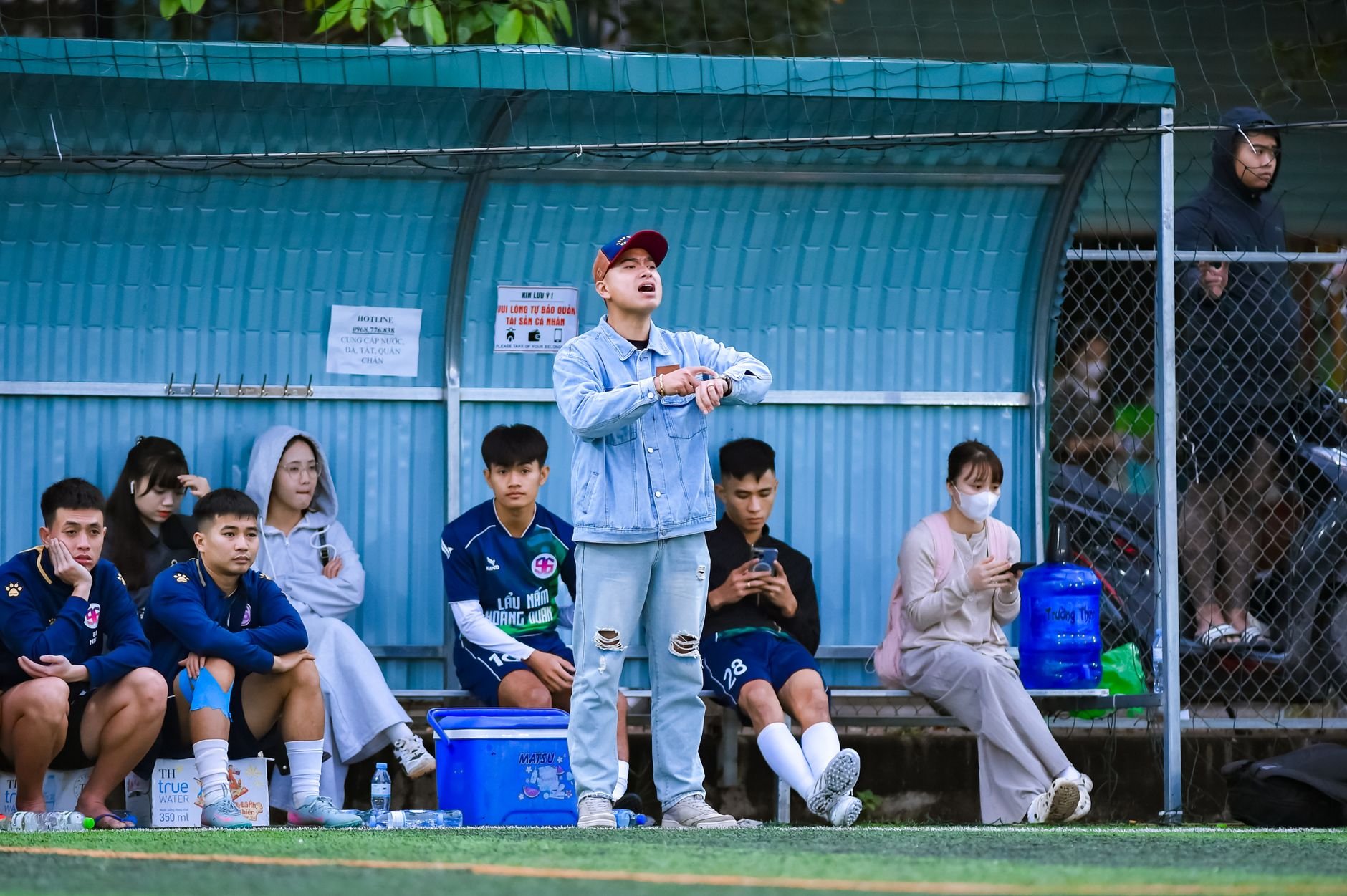 Soccer players and coach on the sidelines at a sports field